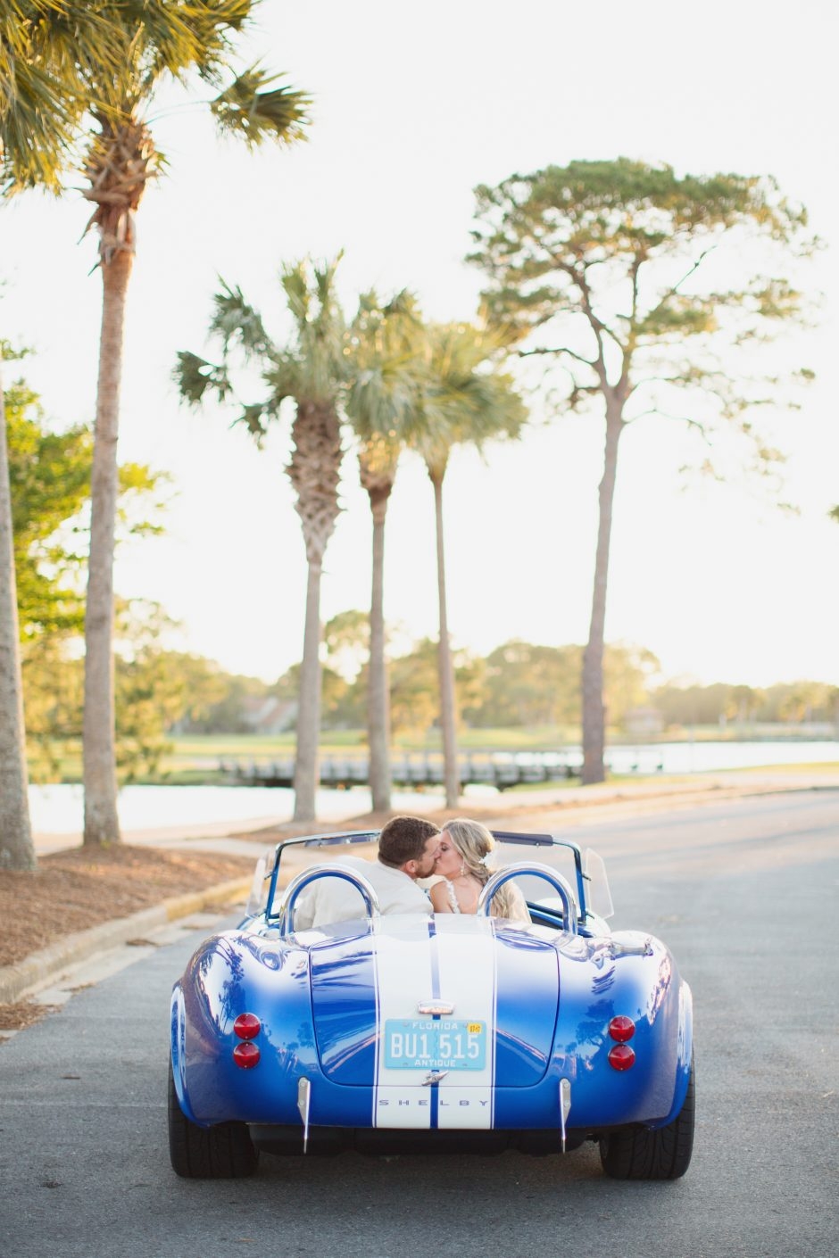 Bride and groom kissing in convertible 