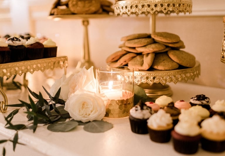 treat table at a wedding reception with flowers, candles and cupcakes