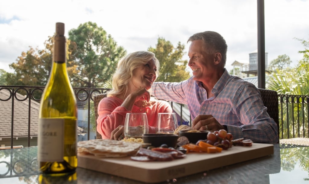 couple enjoys a bottle of wine and charcuterie board on a patio