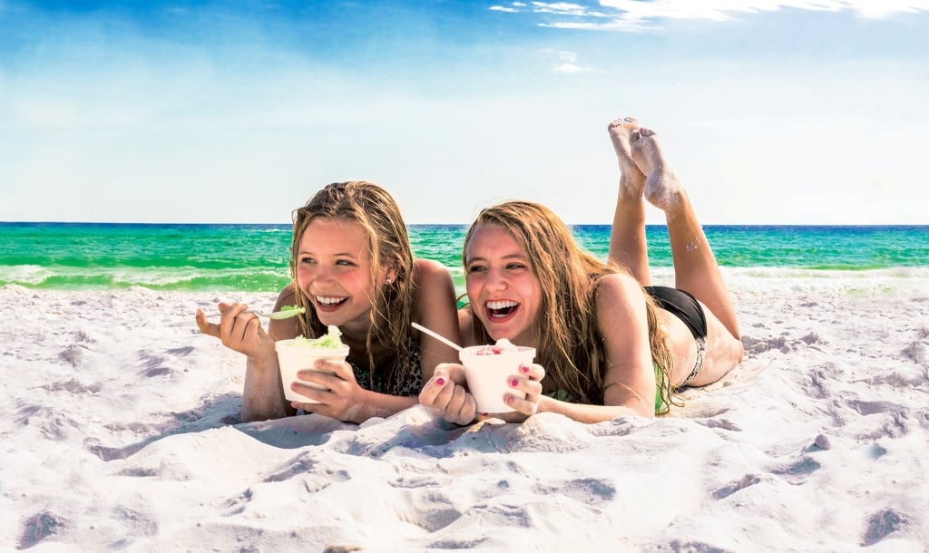 girls laying in the sand eating sno-cones
