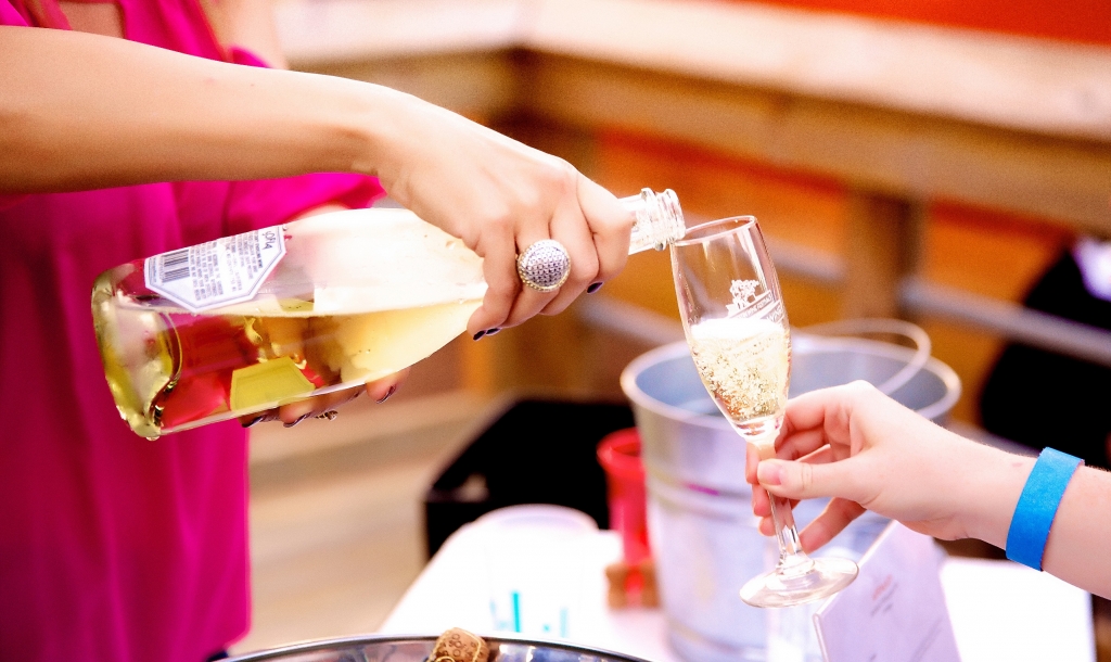 a woman pouring a glass of sparkling wine of a guest