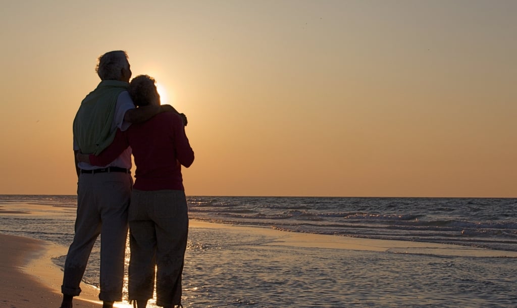 A couple standing on the beach at Sandestin Golf and Beach resort with a beautiful sunset in the background