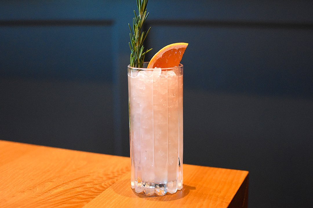 Fancy cocktail with an orange slice and sprig of rosemary