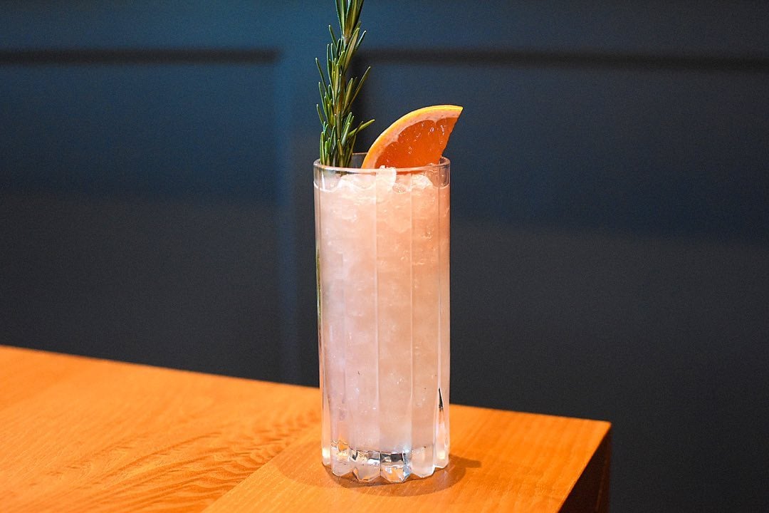 Fancy cocktail with an orange slice and sprig of rosemary