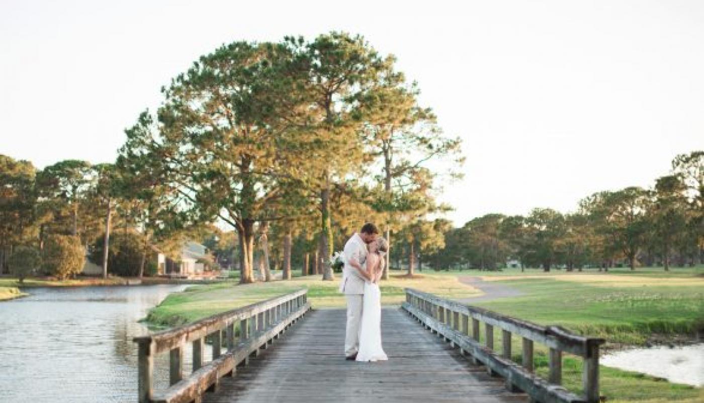Bride and groom kissing on bridge