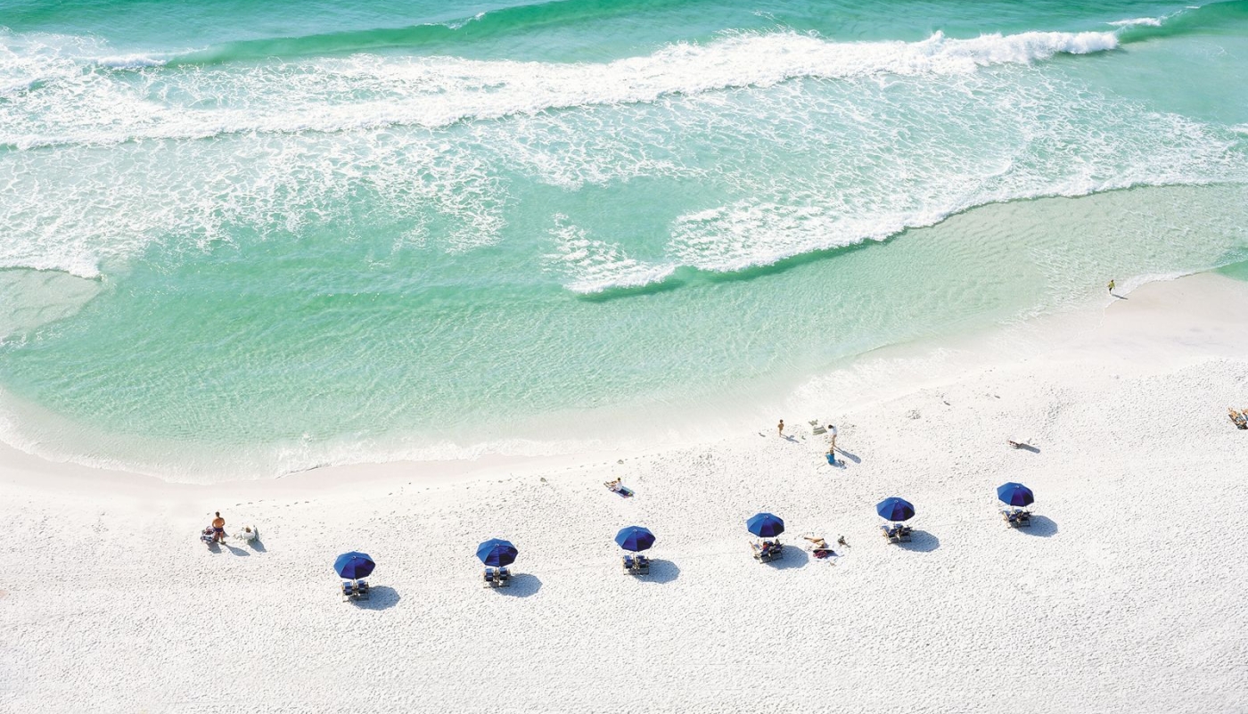 Beach chair umbrellas lined up in a row on the beach