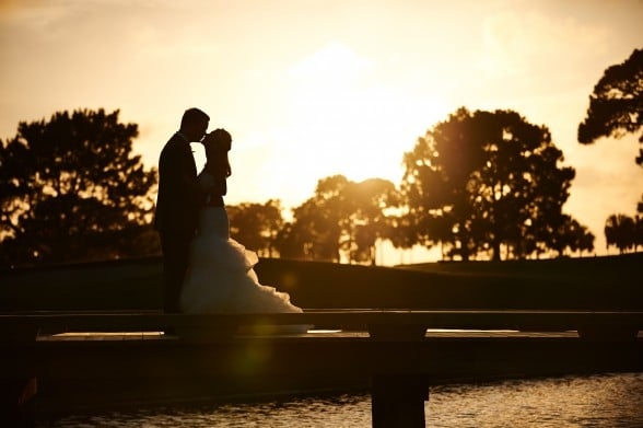 Bride and groom kissing on golf course at sunset