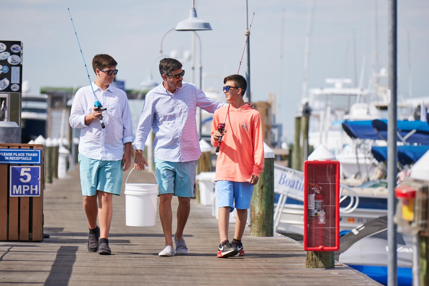 Father and sons walking along a dock together.