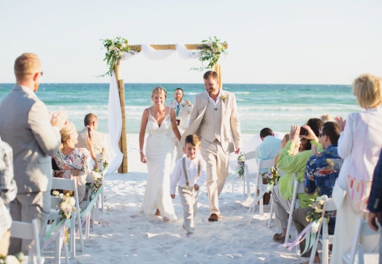 Bride and groom walking down beach wedding isle