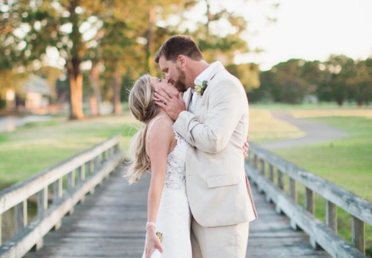 Bride and groom kissing on bridge