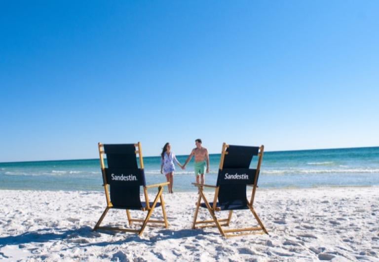 couple walking on the beach with beach chairs in the foreground 