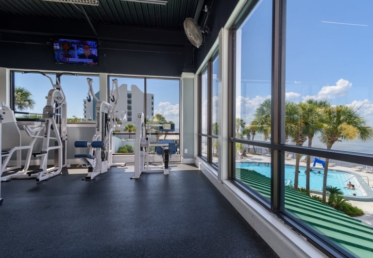 fitness equipment in front of a large window overlooking a pool