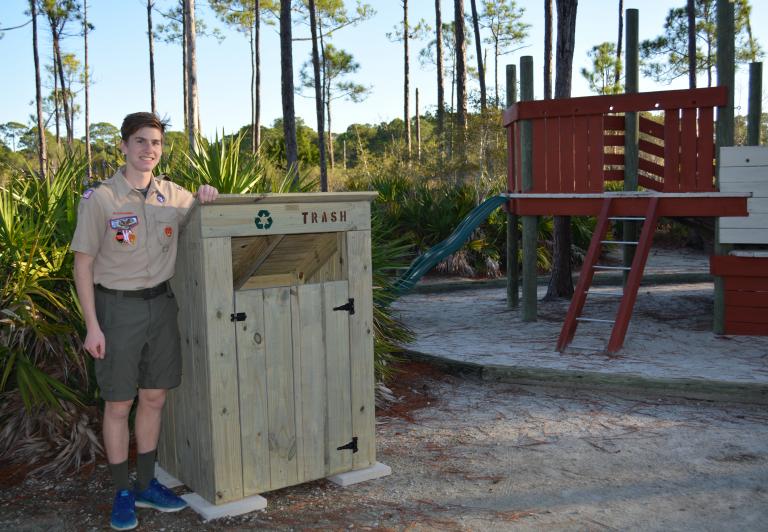 Park employee standing beside a garbage can