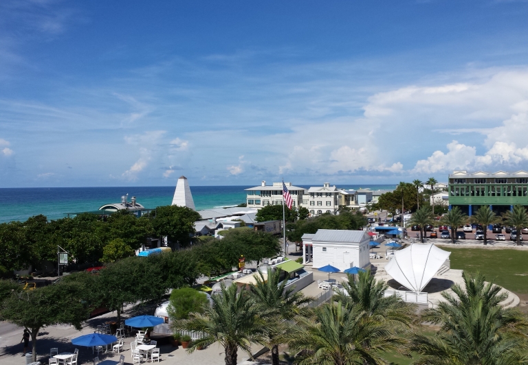 view from a balcony overlooking the ocean with palm trees in the foreground.
