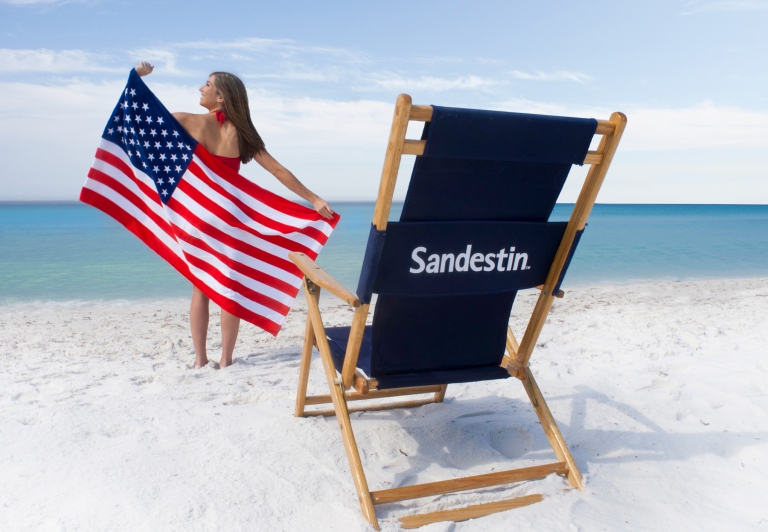 Woman on the beach with an American flag and beach chair
