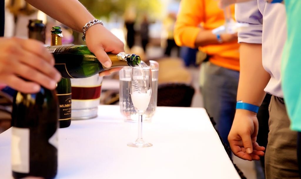 a person pouring a glass of champagne at a public event
