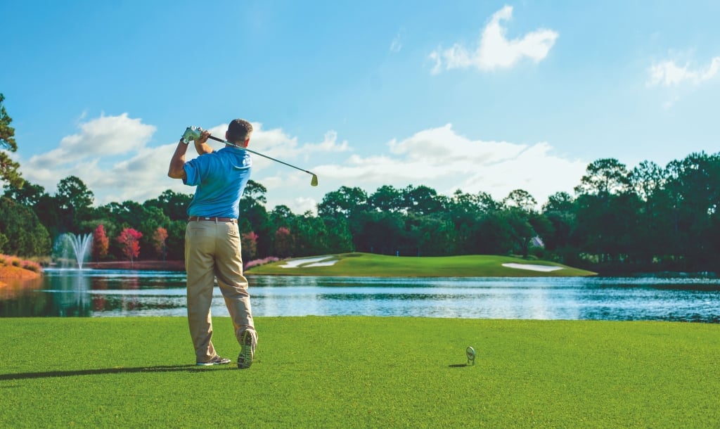 a man tees off at Raven golf course