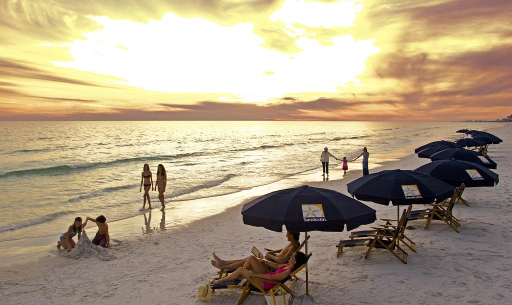 groups of people relaxing on the beach with the sunset in the background 