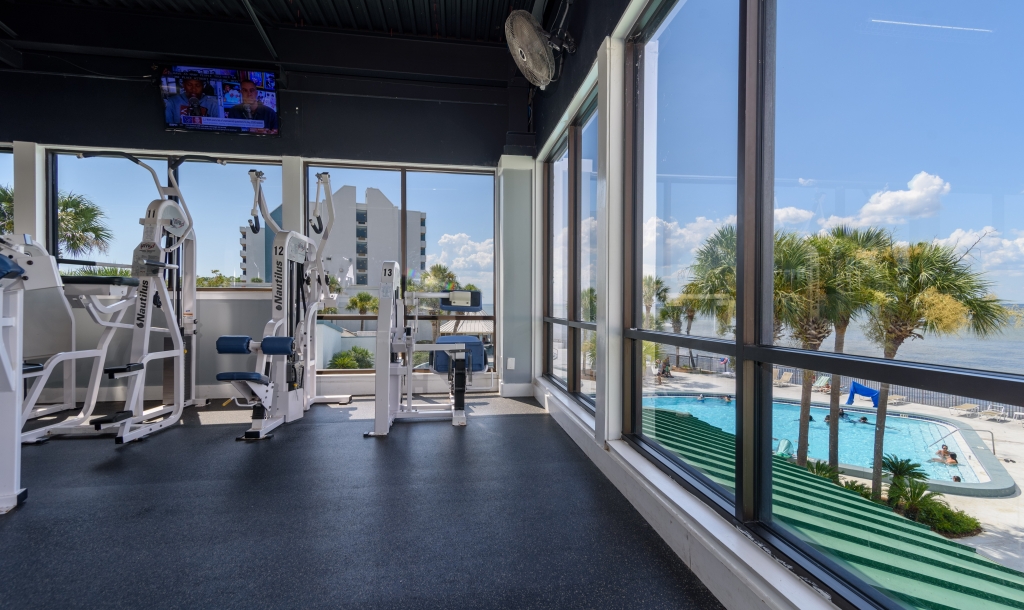 fitness equipment in front of a large window overlooking a pool