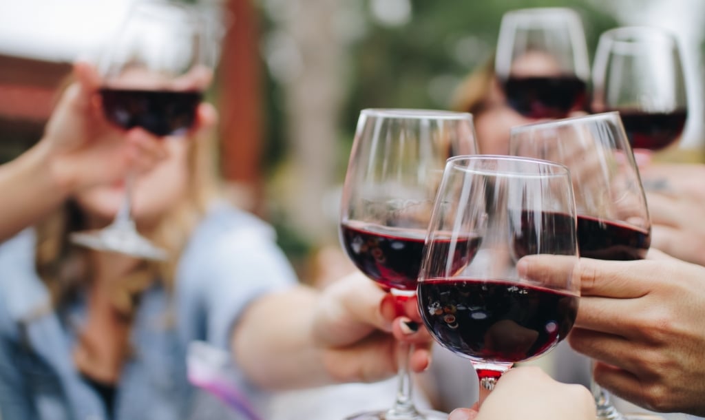 table of guests cheersing wine glasses