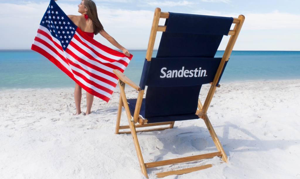 Woman on the beach with an American flag and beach chair