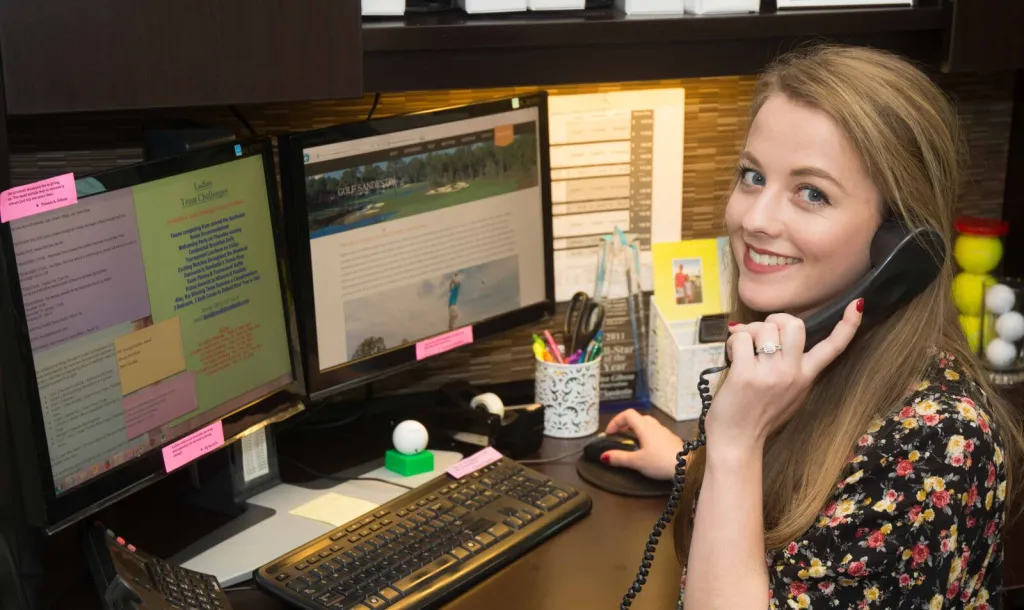 a Sandestin Employee sitting at an office desk on the phone