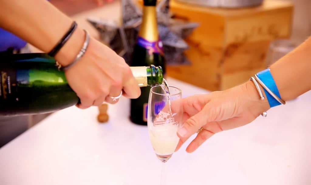 a woman pouring a glass of sparkling wine of a guest