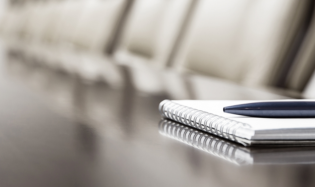 pen and pad of paper on a boardroom table