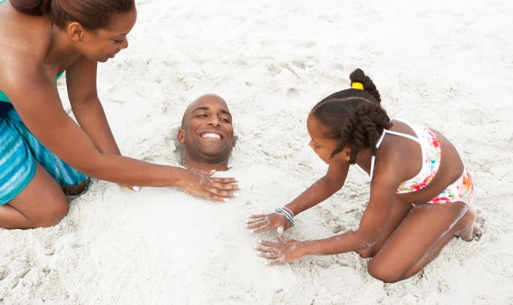 Family burying dad in the sand
