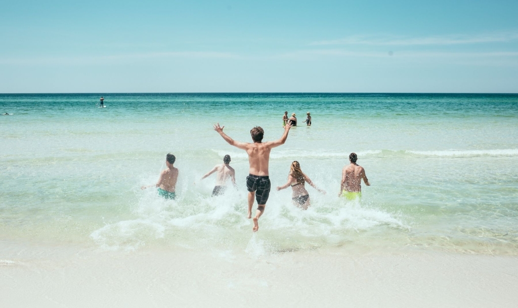 friends running into beach water
