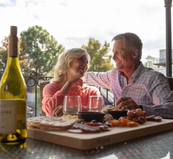 older man and woman enjoying dinner on a patio