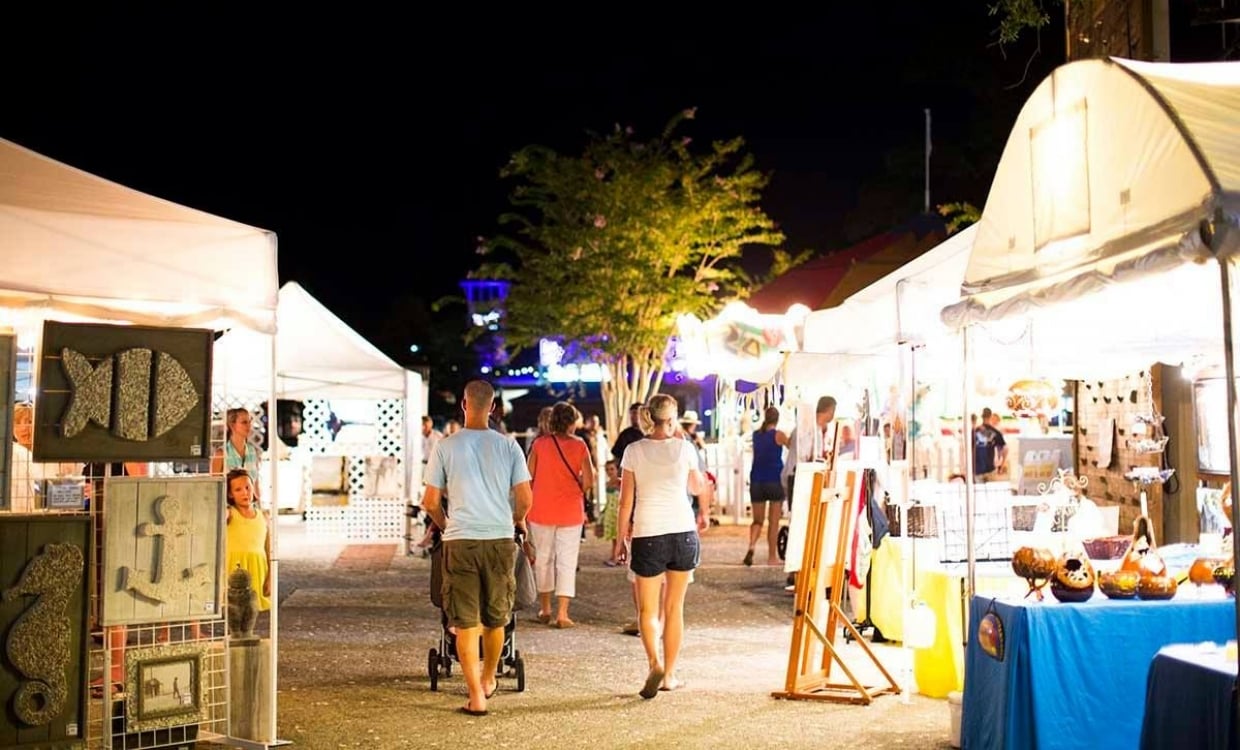 Guests exploring outdoors art exhibits at night time 