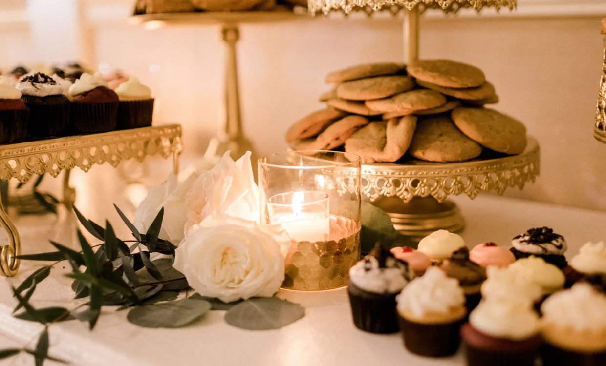 treat table at a wedding reception with flowers, candles and cupcakes