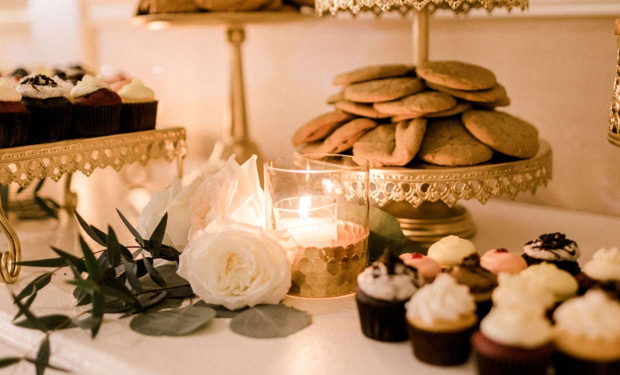 treat table at a wedding reception with flowers, candles and cupcakes