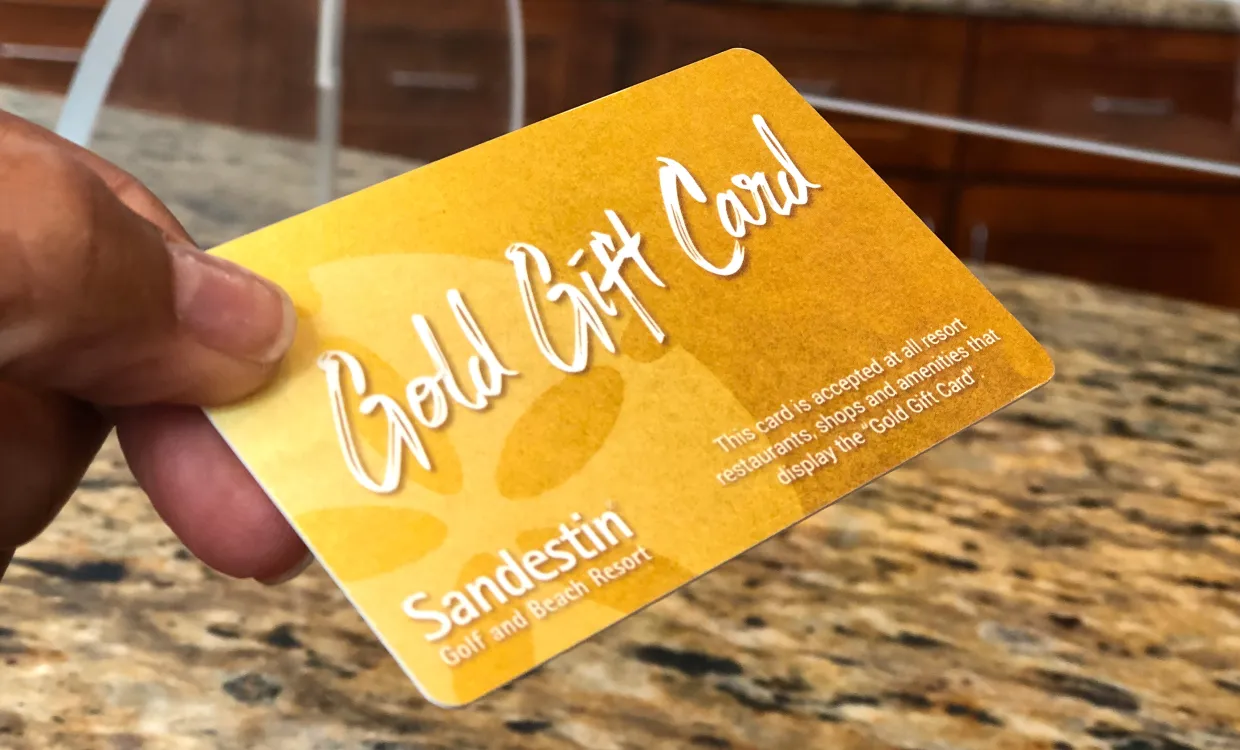 Person handing a gift card over a counter for a purchase