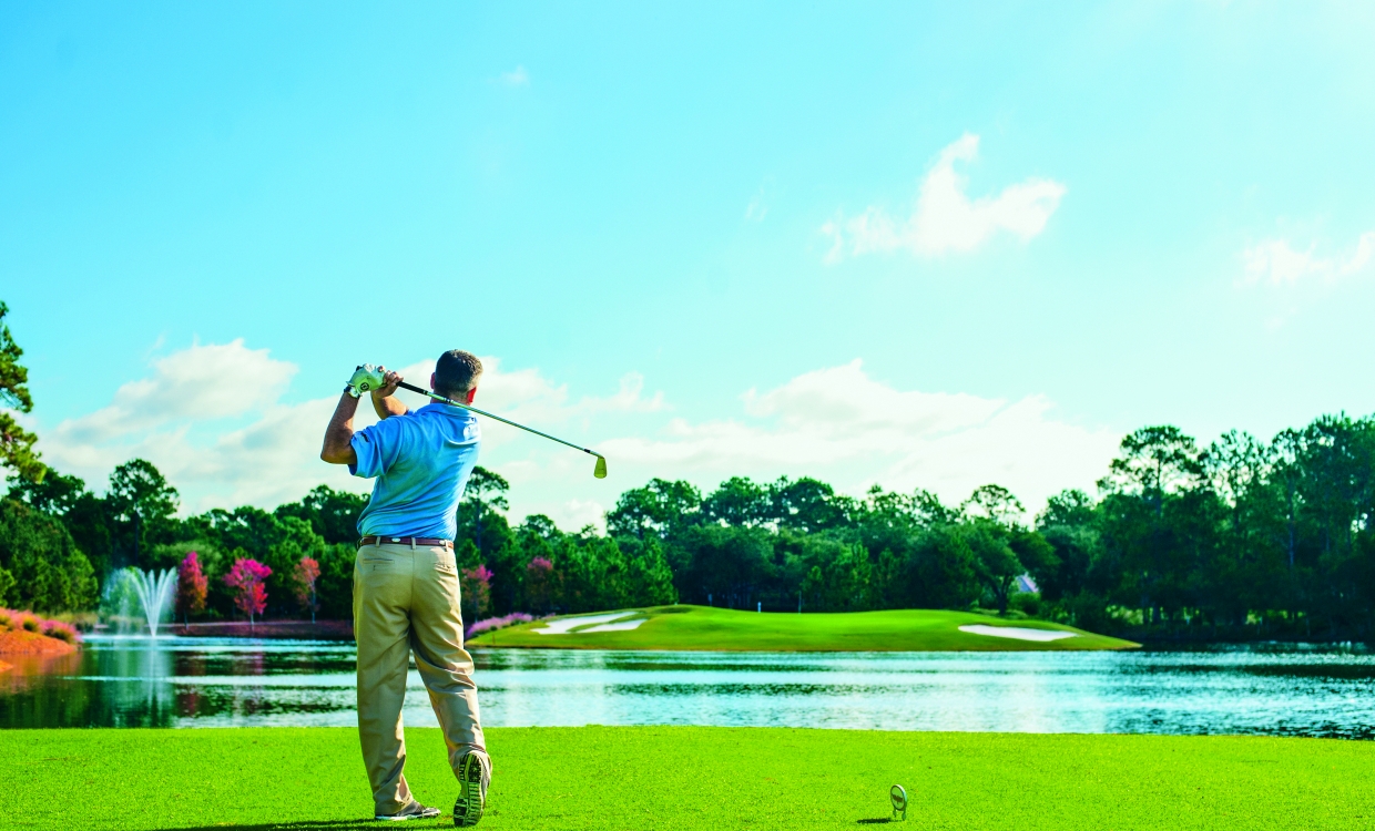 man swinging golf club on course